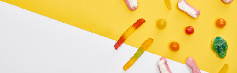 panoramic shot of colorful gummy sweets on yellow and white background, Halloween treat
