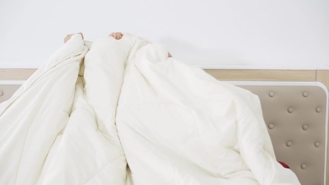 Group of scared teenage girls watching horror movie and hiding under blanket on the bed in bedroom at home. Shot in 4k resolution