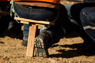 Obraz premium man sitting on makeshift wooden bench showing the sole of his boot