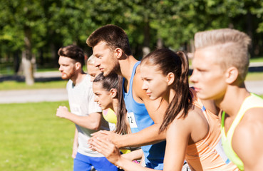 fitness, sport, race and healthy lifestyle concept - group of people or sportsmen with badge numbers on start of running marathon at summer park