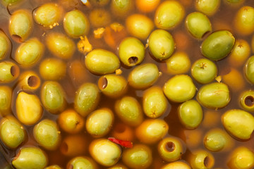 Pickled green olives with hot chili peppers garlic marinated in spicy brine at farmers market. Artisan local produce Mediterranean cuisine appetizers healthy diet concept