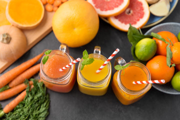 food , healthy eating and vegetarian concept - mason jar glasses of orange and carrot juices with...