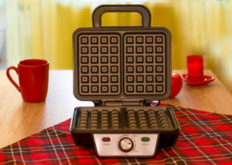 Open electronic waffle-iron. Kitchen view with beautiful red background. Sample model for a kitchen appliance.