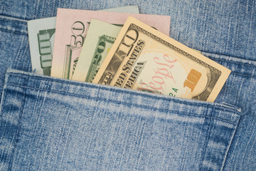 American money dollars in various denominations peep out of a jeans pocket.
