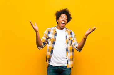 young black man feeling happy, excited, surprised or shocked, smiling and astonished at something...