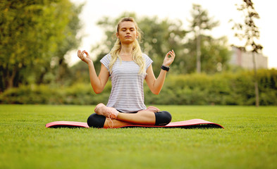 Young woman practicing yoga pose at the park on a beautiful green field
