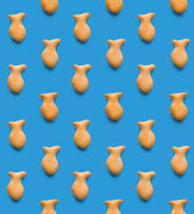Rounded fresh crispy fish shaped cookies on light blue background. Seamless texture. Top view