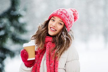 people, hot drinks and christmas concept - happy teenage girl or young woman drinking takeaway coffee outdoors in winter park