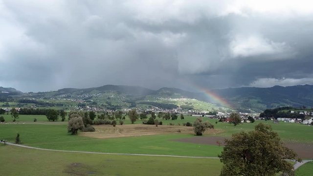 Magical rainbow over the green landscape of Benken Switzerland, aerial shot 