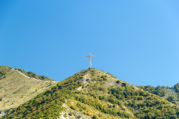 Gelendzhik, Krasnodar region, Russia, September 10. Orthodox worship cross on the hill of Caucasian mountains with chapel in foundation. Day time.