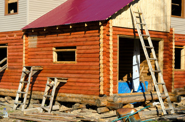 Construction of the facade of a new house made of pine timber with stairs leaning against the walls and Windows in Yakutia.