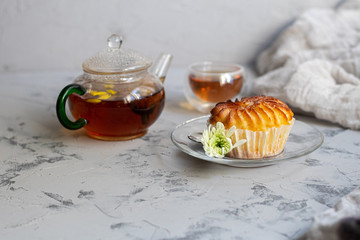 Flower tea with ginger and lime. On a plate are cupcakes with cream filling. Everything is located on a gray background made under granite. 