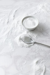 Obraz na płótnie Canvas Baking soda in a bowl and in a spoon on the marble countertop