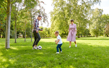 family, leisure and people concept - happy mother, father and little son with ball playing soccer at summer park