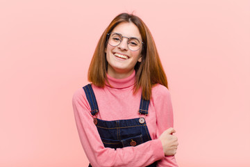 young pretty woman laughing shyly and cheerfully, with a friendly and positive but insecure...