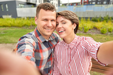 love, valentines day and relationships concept - happy couple in summer park taking selfie outdoors