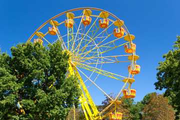 Fototapeta premium Ferris Wheel against blue sky background on sea promenade. Attractions and entertainment during the holidays. Vacation concept.