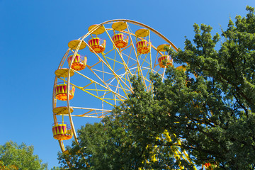 Fototapeta premium Ferris Wheel against blue sky background on sea promenade. Attractions and entertainment during the holidays. Vacation concept.