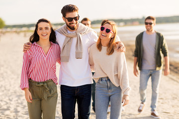 Fototapeta premium friendship, leisure and people concept - group of happy friends walking along beach in summer