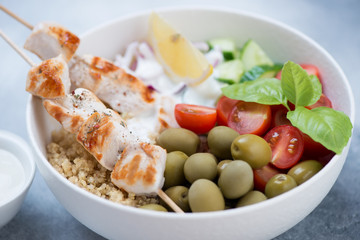 Closeup of greek food bowl with souvlaki skewers and vegetables, selective focus