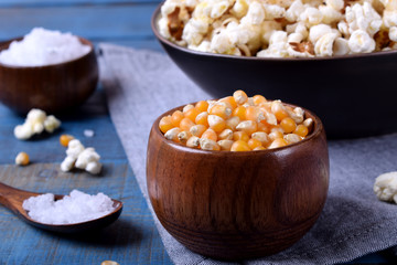Unpopped corn kernels for making popcorn in a wooden cup on blue table