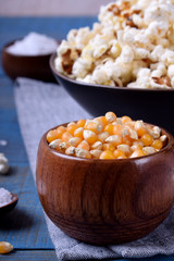 Unpopped corn kernels for making popcorn in a wooden cup on blue table
