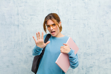young student woman feeling terrified, backing off and screaming in horror and panic, reacting to a...