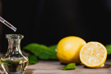 Pouring essential oil into glass bottle on black background, copy space image