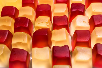 Red and yellow cube shaped jelly candy arranged in checker board pattern. Candy background.