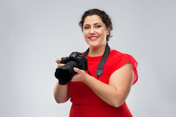 people and photography concept - happy woman photographer in red dress with digital camera over grey background