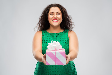 holidays, presents and people concept - happy woman in green dress holding gift box over grey...