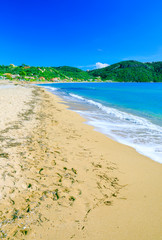 Beautiful summertime panoramic seascape. Awesome view picturesque green slopes coastline sea with crystal clear azure water. Big golden sand beach.