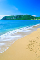 Beautiful summertime panoramic seascape. Awesome view picturesque green slopes coastline sea with crystal clear azure water. Big golden sand beach.