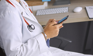 female doctor between patients in the office talking on the pho