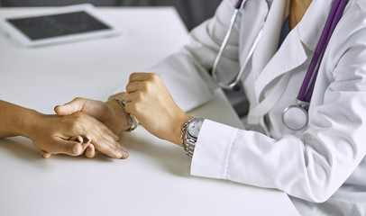 Woman doctor calms patient and holds hand