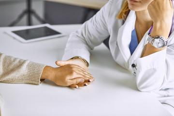 Woman doctor calms patient and holds hand