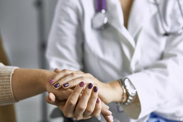 Woman doctor calms patient and holds hand