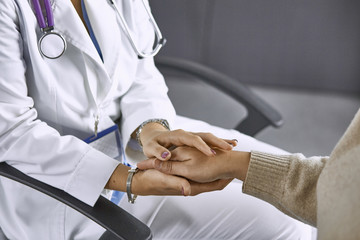 Woman doctor calms patient and holds hand