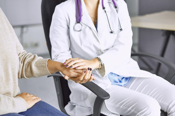 Woman doctor calms patient and holds hand