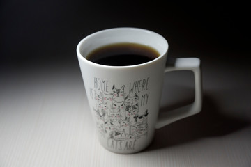Coffee beans, a coffee grinder and a cup of hot coffee.