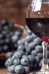 A glass of fragrant red wine and bunches of blue grapes