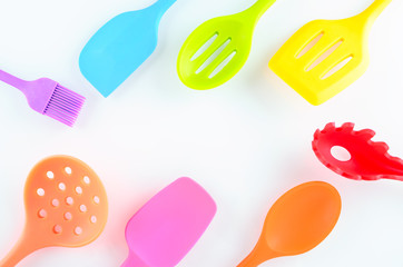 bright multi colored kitchen utensils on white background with copy space