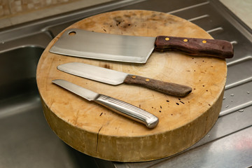 Knives and cleaver prepared for chef on wood cutting board