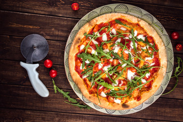 Top view Pizza Margherita with Buffalo mozzarella, tomatoes and fresh basil. Pizza cutter lies on the wooden background. Horizontal flat lay. Traditional italian fast food