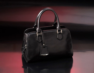 Women's black leather bag on an abstract red background.
