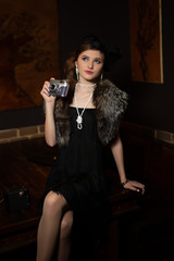 Fototapeta na wymiar Beautiful young girl in an evening dress and a veil in a bar with a retro camera sits on a table