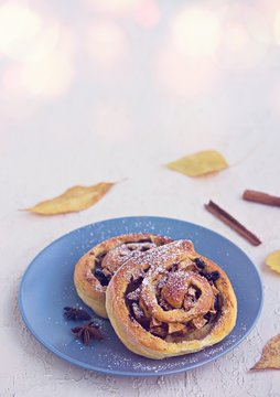 Twisted yeast buns with apples, raisins and cinnamon on a gray plate on a light concrete background. Harvest apples. Recipes with apples.