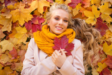Naklejka na ściany i meble Portrait of pretty blonde teen girl lying on the carpet of yellow and red leaves