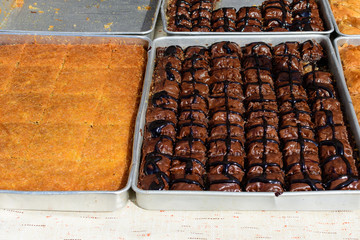 Close up of traditional oriental sweet pastry cookies known as backlava, Turkish desert with sugar, honey, walnuts and pistachio, in display at an weekend street food market, top view, soft focus