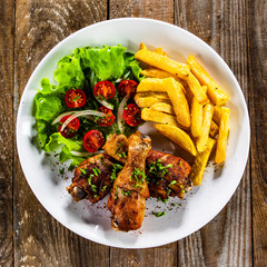 Grilled chicken drumsticks with french fries and vegetables